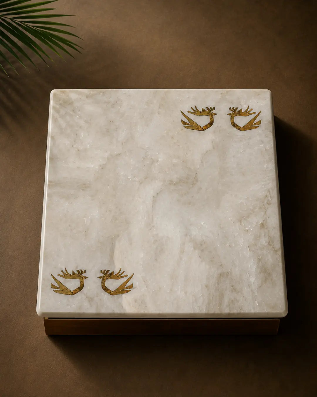 Kamoor White marble table top with hand-inlaid brass birds in flight, photographed from above in a minimal luxury setting.