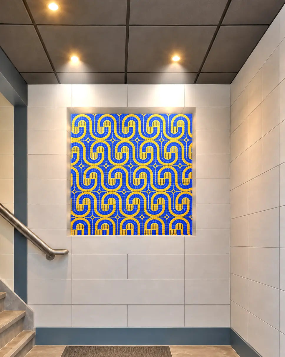Blue and yellow geometric vitreous glass mosaic installed in a recessed stairway wall niche.
