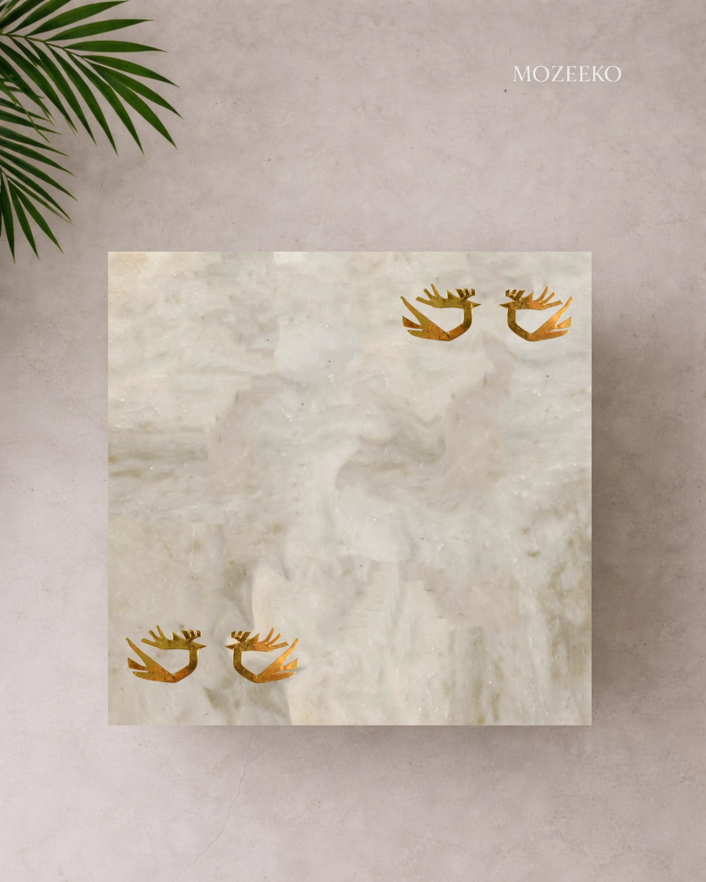 Kamoor White marble table top with hand-inlaid brass birds in flight, photographed from above in a minimal luxury setting.