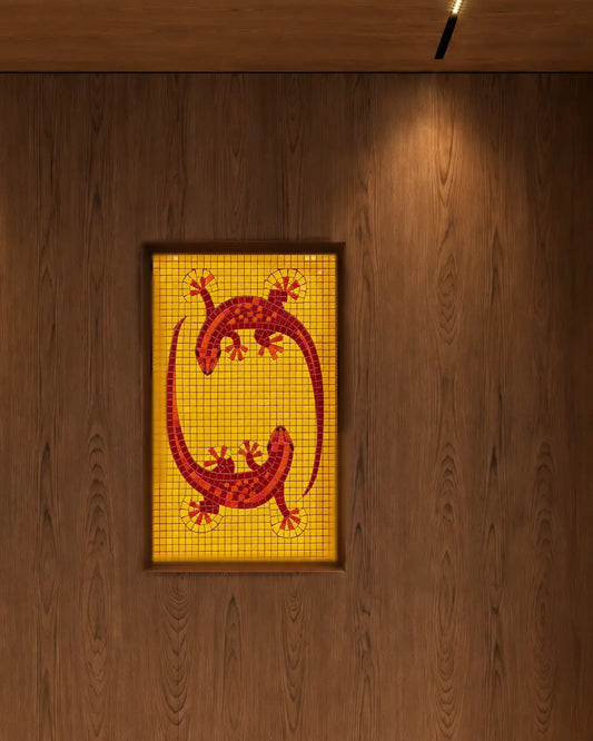 Two red lizards on a yellow vitreous glass mosaic panel installed in a recessed wooden feature wall.